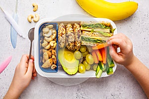 School healthy lunch box with sandwich, cookies, fruits and avocado on white background