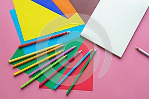 School and hobby concepts. Colored paper sheets, colored pencils and open sketchbook