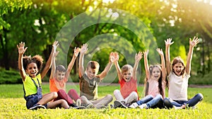 School holidays. Group of happy children sitting on green grass