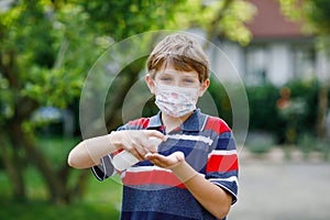 School kid boy with medical mask as protection against pandemic coronavirus quarantine disease. Child holding bottle