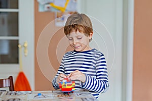 School kid boy playing with lots of small colorful plastic blocks