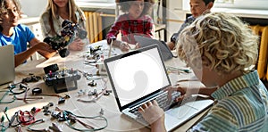 School kid boy using laptop computer with mockup screen sitting at STEM class.