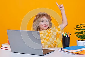 School kid holding index finger up with great new idea. School child using laptop computer.