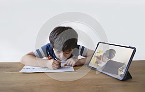 School Kid using pen drawing cartoon on paper, Child sitting alone doing home work, Young boy using digital pad searching