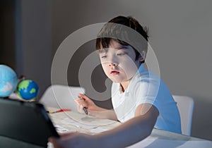 School kid using tablet for his homework,Child boy doing homework by using digital tablet searching information on internet after