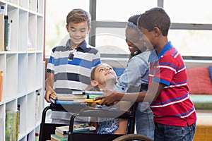 School kids giving books to disabled girl in library