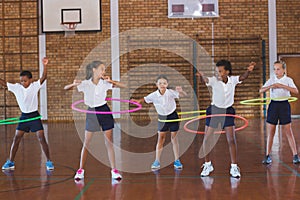 School kids playing with hula hoop in in basketball court