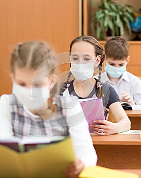 School kids with protective mask on faces against virus in classroom