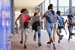 School kids running in elementary school hallway, back view