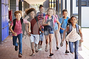 School kids running in elementary school hallway, front view