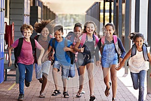 School kids running in elementary school hallway, front view