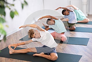 School kids training during yoga class on yoga mats.