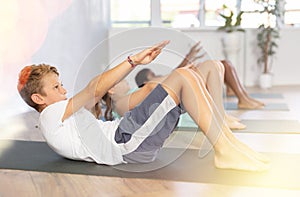 School kids training yoga on yoga mat in gym.