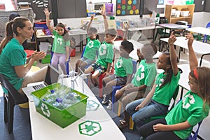 School kids wearing recycle tee-shirt raising hand to answer at a question