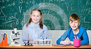 School laboratory. Girl and boy smart students conduct school experiment. Describe chemical reaction notepad. School