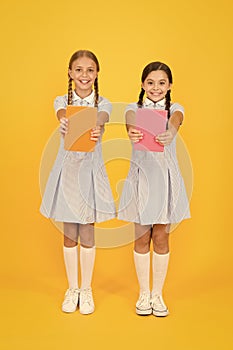 School library. Homeschooling concept. Literacy club. Cute children holding books on yellow background. Little girls