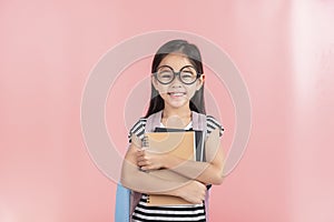 School little girl wearing a glasses carry a bag with backpack hold a books isolated on Pink background