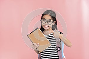 School little girl wearing a glasses carry a bag with backpack hold a books isolated on Pink background