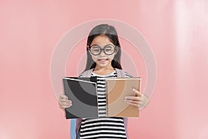 School little girl wearing a glasses carry a bag with backpack hold a books isolated on Pink background