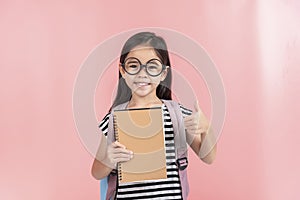 School little girl wearing a glasses carry a bag with backpack hold a books isolated on Pink background