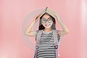 School little girl wearing a glasses carry a bag with backpack hold a books isolated on Pink background