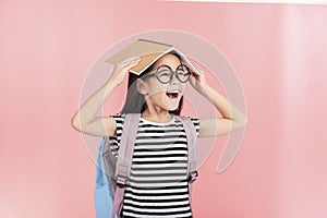 School little girl wearing a glasses carry a bag with backpack hold a books isolated on Pink background