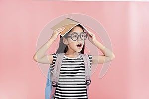 School little girl wearing a glasses carry a bag with backpack hold a books isolated on Pink background