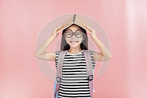 School little girl wearing a glasses carry a bag with backpack hold a books isolated on Pink background