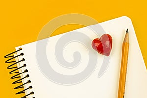 School love letter concept with notepad and pencil, red one heart on white paper, yellow table top view photo with copy
