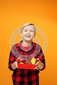 School lunch box with fruit, smiling child holding a fruit box.