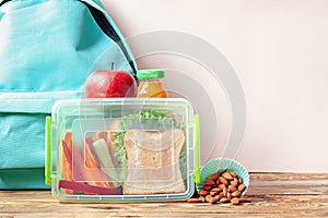 School lunch box with sandwich, vegetables, juice and almonds on table