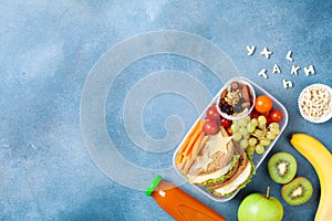 School lunch box with vegetables, fruits and sandwich for healthy snack on table top view.