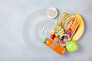 School lunch box with vegetables, fruits and sandwich on table top view.