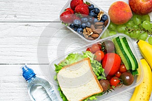 School lunch boxes with sandwich, fruits, vegetables and bottle of water and copy space