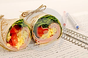 School lunch: ham and cheese wrap sandwich on notebook