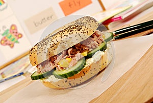 School lunch: tuna bagel sandwich on classroom desk with white board