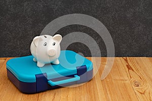 School lunchbox with a piggy bank on wood desk with a chalkboard photo