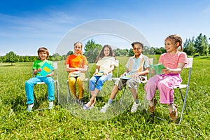 School mates hold exercise books sitting outside