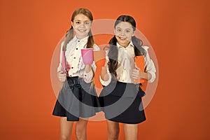 School mates relaxing with drink. Enjoy being pupil. Girls kids school uniform orange background. Schoolgirl hold book