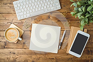 School notebook with coffee cup, smartphone and plant on wooden table. Top view from above