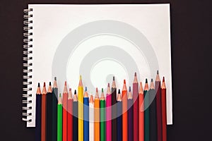 School notebook, Rainbow colored pencils are jiggling side by side. School accessories