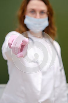 School nurse in a medical mask points her index finger at you. School quarantine education concept