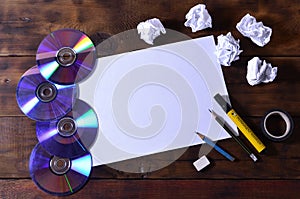 A school or office still life with a white blank sheet of paper and many office supplies. The school supplies lie on a brown wood