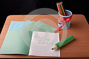 School and office supplies on classroom table in front of blackboard. View with copy space