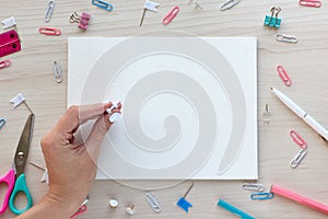 School office supplies on wooden background. Back to school concept. White board with hands for copy space. Top view