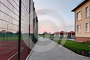 School of preschool building yard with basketball court surrounded with high protective fence