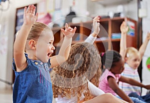 School, raise hands and children in a classroom for education or knowledge at daycare. Kindergarten, happy and young kid