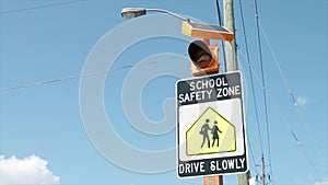 school safety zone drive slowly sign with illustration of people walking