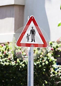 School Safety Zone Roadside Warning Sign - black silhouettes on a white background in a red triangle