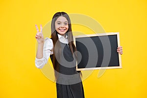 School sales board. Cheerful teenage girl kid hold blackboard chalkboard with copy space on yellow background. Happy